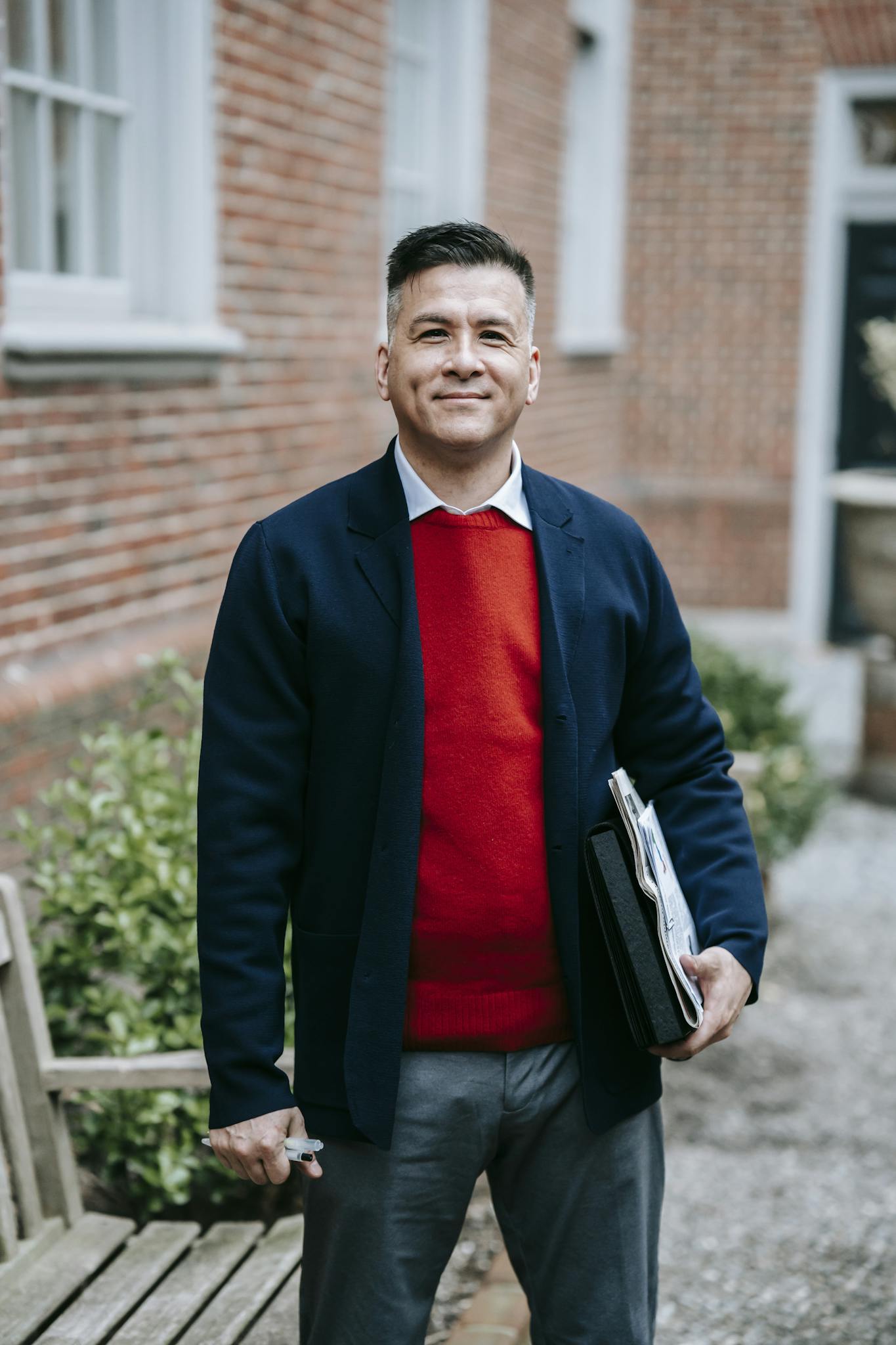 Confident business professional standing outdoors holding a notebook, exuding competence and style.